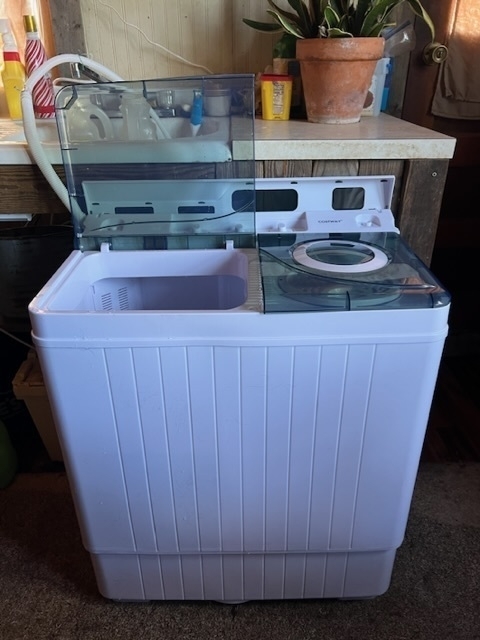 A small white wash machine with two sections, each with a transparent gray lid