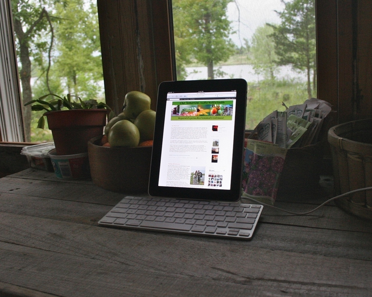 An  original iPad docked in Apple's Keyboard Stand sitting on a rustic wood table 